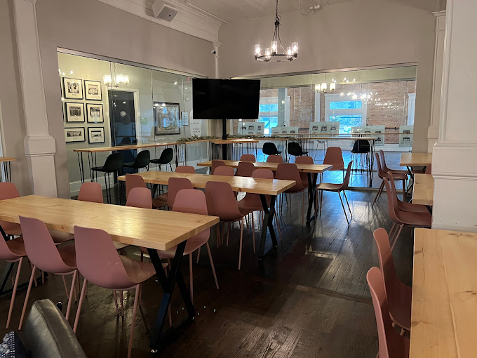 Event seating area with tables, chairs, chandelier, and glass wall at Flourish Taproom